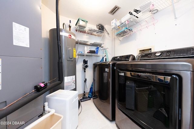 clothes washing area featuring electric water heater and washer and clothes dryer