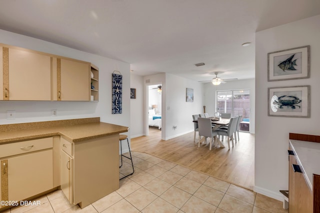 805 Spruce St, New Smyrna Beach, FL 32168 - kitchen featuring cream cabinets, ceiling fan, light tile patterned floors, open shelves, and a kitchen breakfast bar