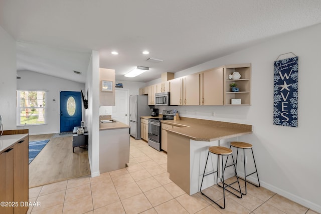 805 Spruce St, New Smyrna Beach, FL 32168 - kitchen with stainless steel appliances, a breakfast bar, a peninsula, lofted ceiling, and recessed lighting