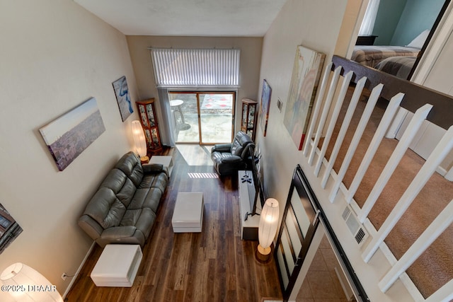 living area with wood finished floors and a towering ceiling