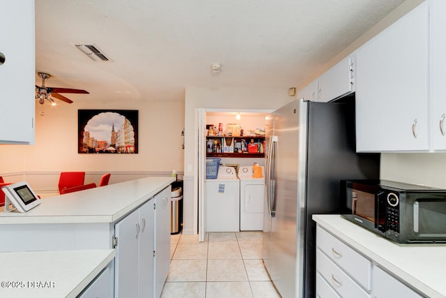 kitchen featuring visible vents, black microwave, washing machine and dryer, light countertops, and freestanding refrigerator