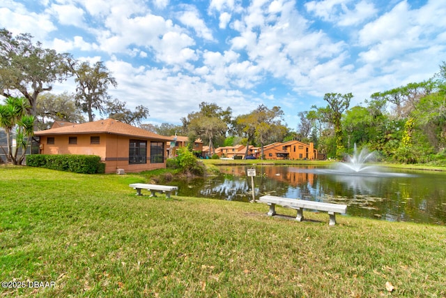 view of property's community with a water view and a lawn