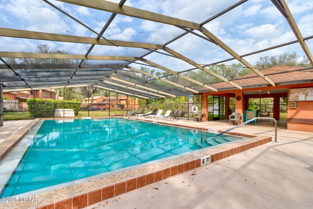 community pool featuring glass enclosure, a patio area, and fence