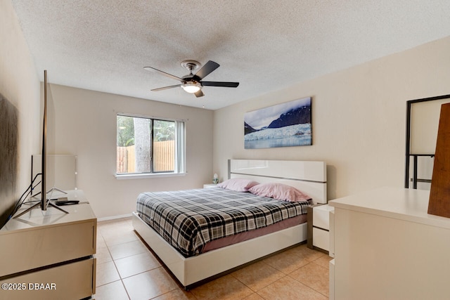 bedroom featuring light tile patterned floors, baseboards, a textured ceiling, and ceiling fan