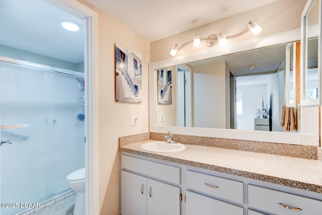 full bath featuring vanity, a textured ceiling, a shower stall, and toilet