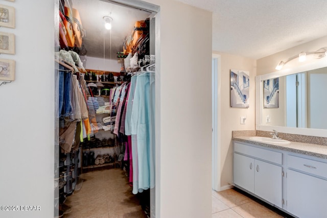 spacious closet with a sink and light tile patterned floors