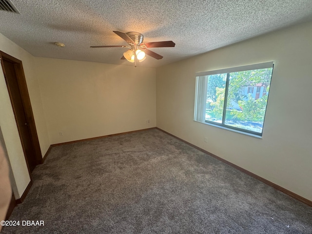 unfurnished room with ceiling fan, a textured ceiling, and dark colored carpet