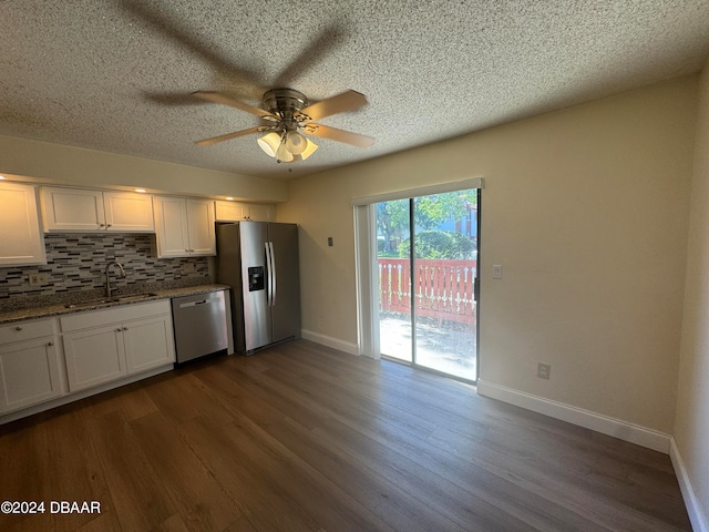 kitchen with stainless steel appliances, dark stone counters, dark hardwood / wood-style floors, white cabinets, and decorative backsplash