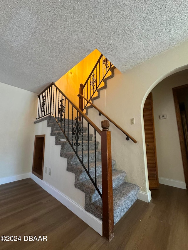 staircase featuring hardwood / wood-style floors and a textured ceiling