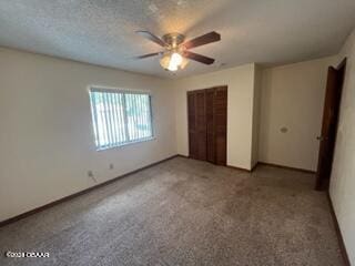 unfurnished bedroom featuring ceiling fan, a textured ceiling, a closet, and carpet