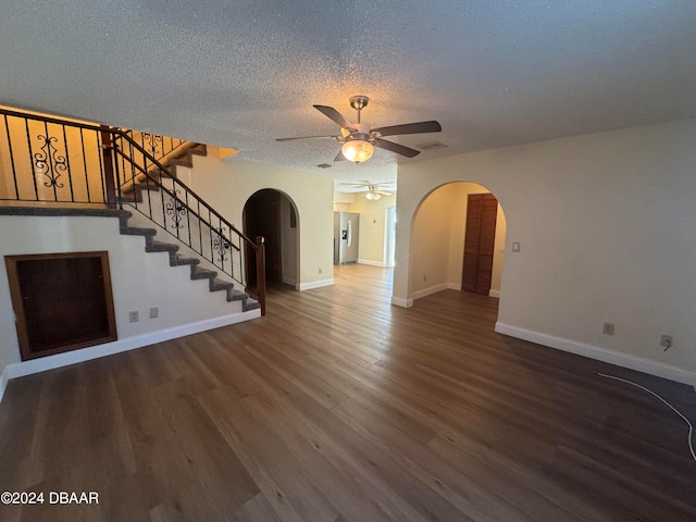 unfurnished living room featuring ceiling fan, a textured ceiling, and dark hardwood / wood-style floors