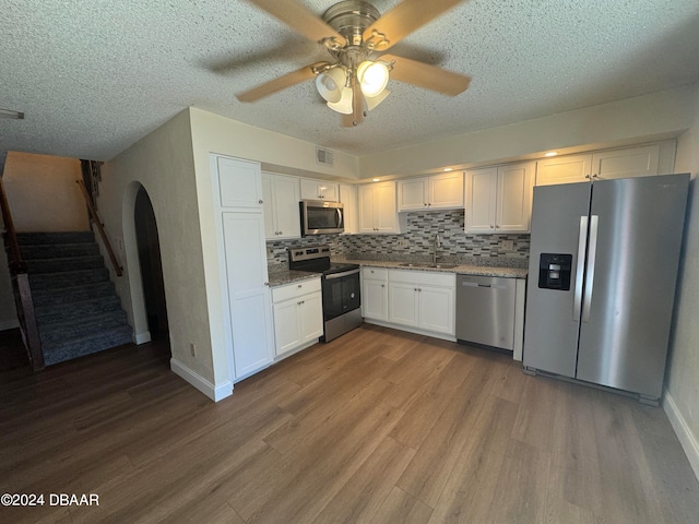 kitchen featuring wood-type flooring, sink, ceiling fan, white cabinetry, and appliances with stainless steel finishes