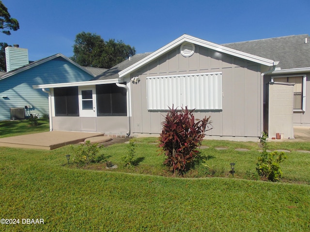 view of side of home with central AC unit, a patio, and a yard