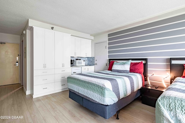 bedroom featuring a textured ceiling and light hardwood / wood-style flooring