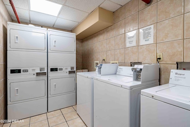 laundry room featuring stacked washing maching and dryer, tile walls, light tile patterned floors, and independent washer and dryer