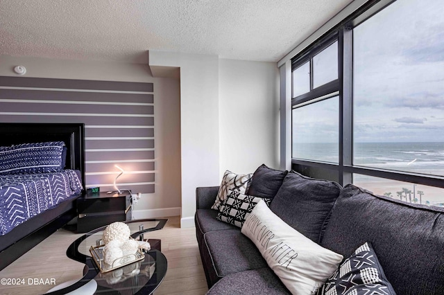 bedroom featuring a textured ceiling, a beach view, a water view, and hardwood / wood-style flooring