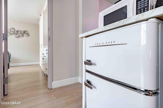 details with hardwood / wood-style flooring and white fridge