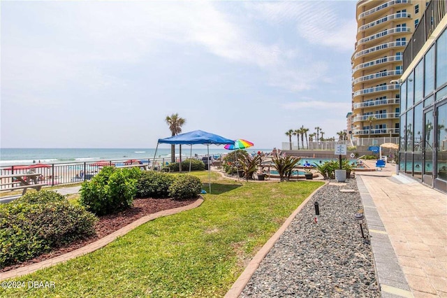 view of property's community with a swimming pool, a water view, and a lawn