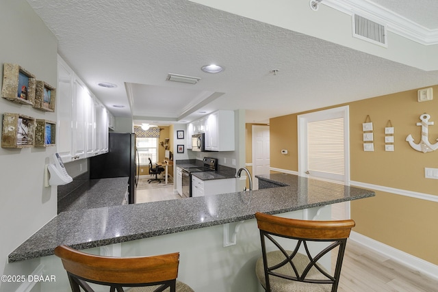 4650 Links Village Dr Unit C-505, Ponce Inlet, FL 32127 - kitchen featuring range with electric cooktop, stainless steel microwave, light wood-type flooring, a peninsula, and a kitchen bar