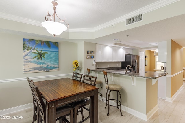 4650 Links Village Dr Unit C-505, Ponce Inlet, FL 32127 - dining room featuring crown molding, light wood-style flooring, a raised ceiling, and baseboards