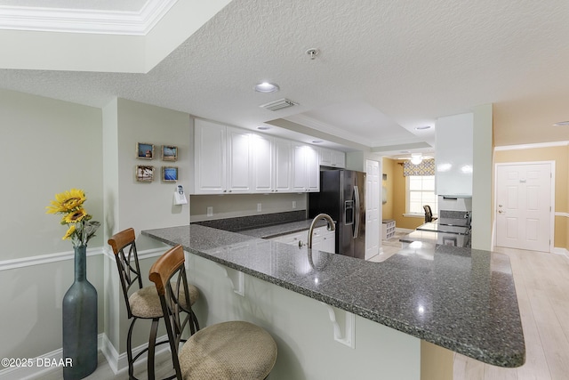 4650 Links Village Dr Unit C-505, Ponce Inlet, FL 32127 - kitchen featuring black fridge, a peninsula, ornamental molding, baseboards, and light wood-style floors