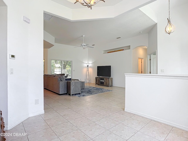 unfurnished living room with a high ceiling, ceiling fan with notable chandelier, and light tile patterned flooring