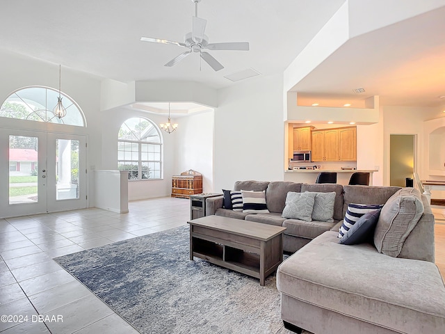 tiled living room with french doors and ceiling fan with notable chandelier