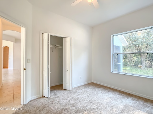 unfurnished bedroom with ceiling fan, a closet, and light carpet