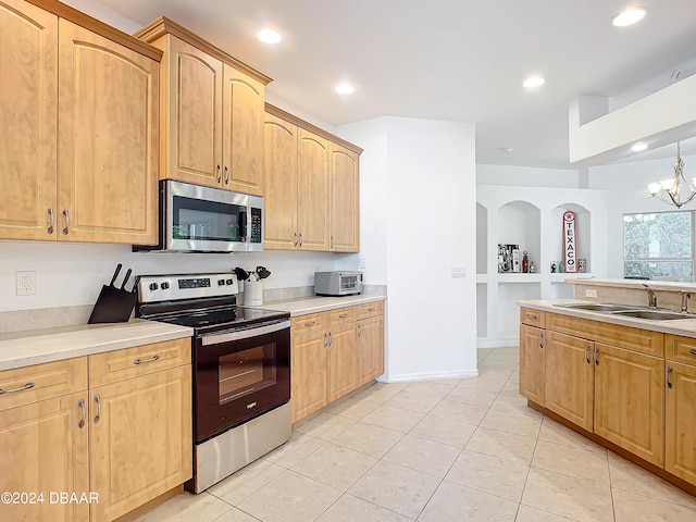 kitchen featuring appliances with stainless steel finishes, sink, light tile patterned floors, pendant lighting, and a chandelier