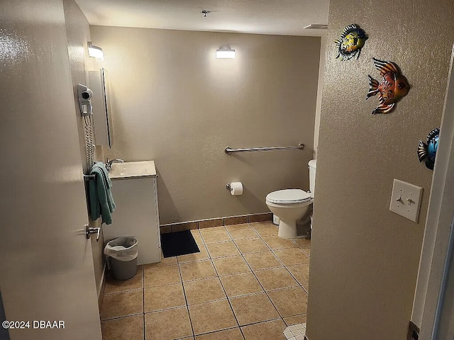 bathroom with toilet, vanity, and tile patterned flooring