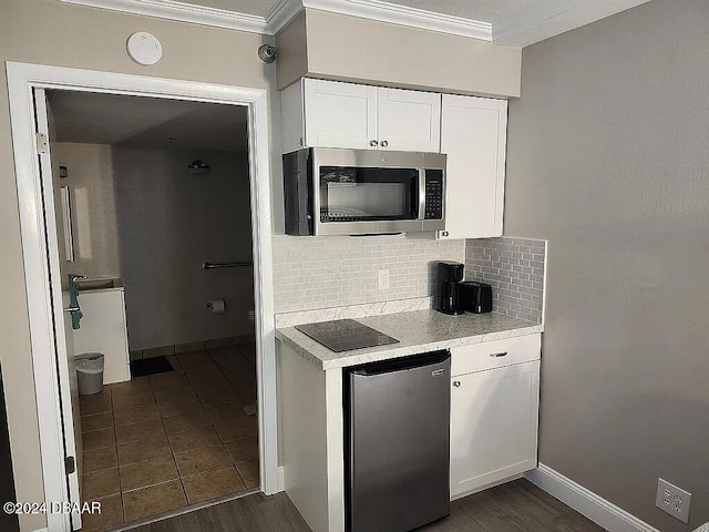 kitchen with white cabinets, decorative backsplash, crown molding, and stainless steel appliances