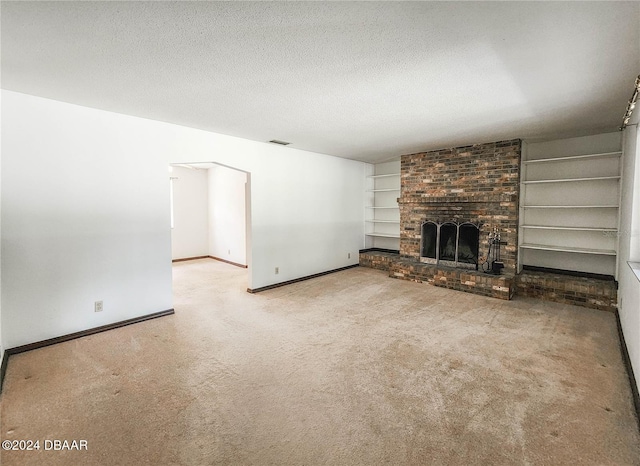 unfurnished living room with carpet, built in features, a brick fireplace, and a textured ceiling