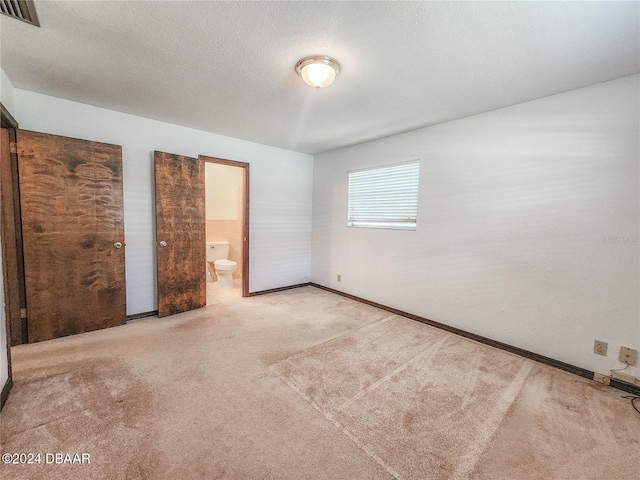1119 Indigo Rd, Ormond Beach, FL 32174 - unfurnished bedroom with carpet floors, baseboards, connected bathroom, and a textured ceiling
