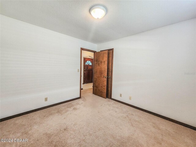 carpeted empty room with a textured ceiling