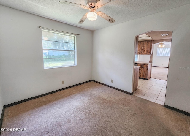 unfurnished room featuring a textured ceiling, ceiling fan, and light colored carpet