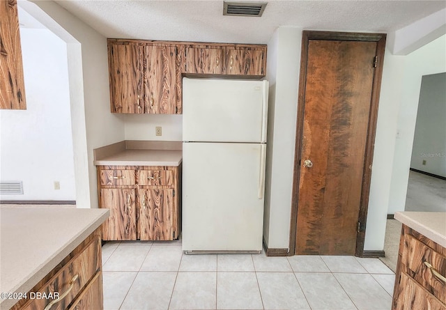 kitchen featuring a textured ceiling, light tile patterned floors, and white fridge