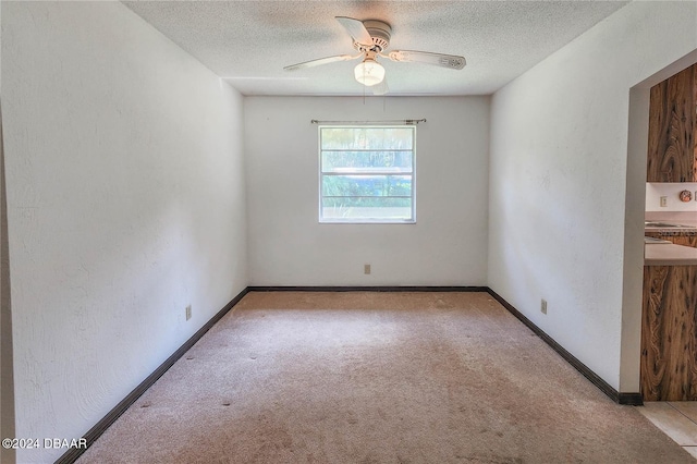 unfurnished room with ceiling fan, light colored carpet, and a textured ceiling