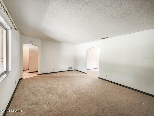 empty room featuring light colored carpet and a textured ceiling