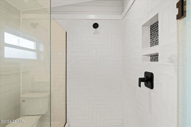 bathroom with a tile shower and toilet