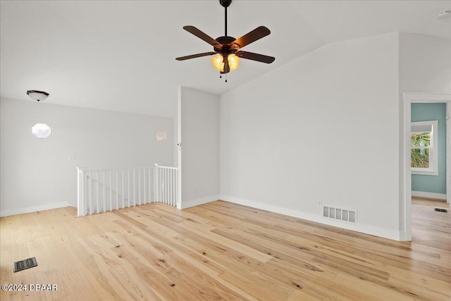 empty room with ceiling fan, vaulted ceiling, and light hardwood / wood-style flooring