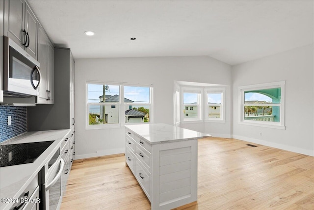 kitchen featuring stainless steel appliances, a kitchen island, a healthy amount of sunlight, and light hardwood / wood-style floors