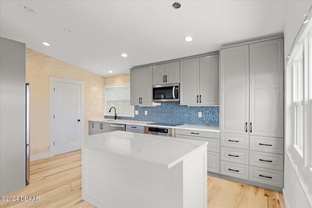 kitchen featuring a center island, stainless steel appliances, vaulted ceiling, and light hardwood / wood-style floors