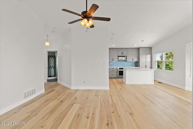 unfurnished living room featuring light wood-type flooring, ceiling fan, and lofted ceiling