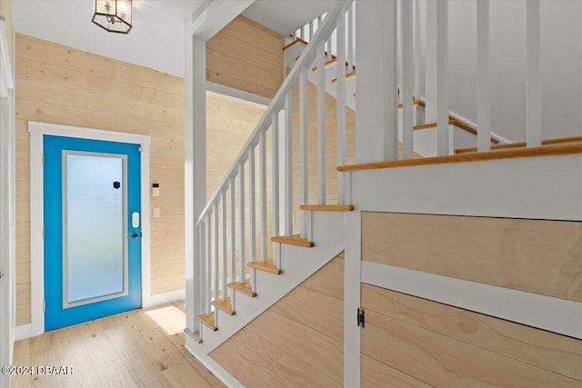 staircase featuring wooden walls and hardwood / wood-style flooring