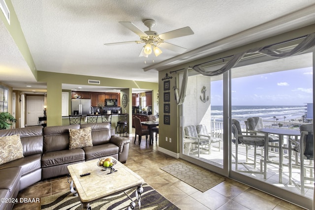 2071 S Atlantic Ave Unit 605, Daytona Beach, FL 32118 - tiled living area featuring a textured ceiling, a ceiling fan, a water view, and baseboards