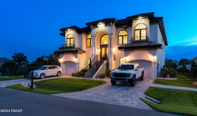 mediterranean / spanish-style house featuring a garage, a lawn, and a balcony