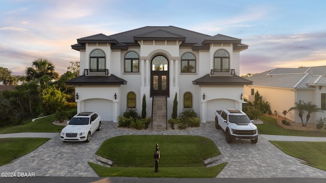 mediterranean / spanish-style home featuring a balcony, a garage, and a lawn