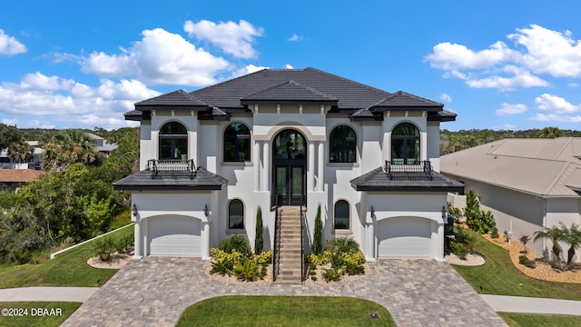 mediterranean / spanish-style home with a garage, a front yard, and a balcony