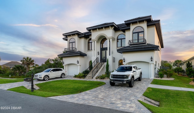 view of front of property with a garage, a yard, and a balcony