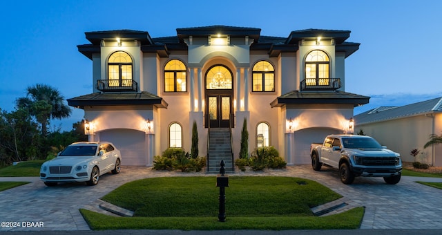 view of front facade with a garage, a lawn, and a balcony